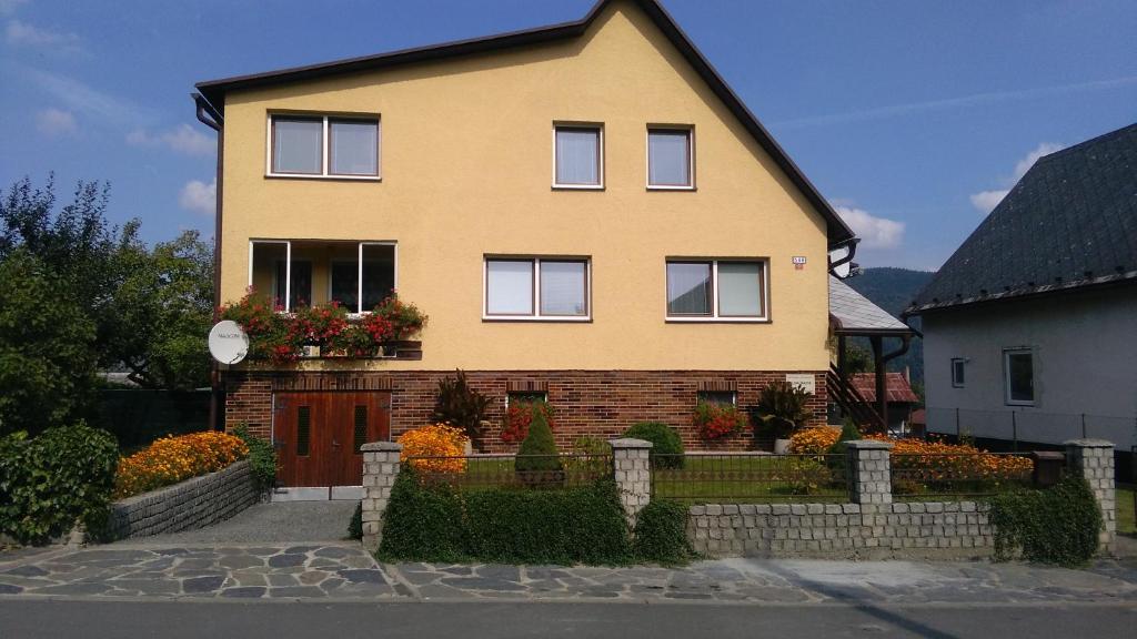 a yellow house with flowers in front of it at Ubytování - Žáková in Vrbno pod Pradědem