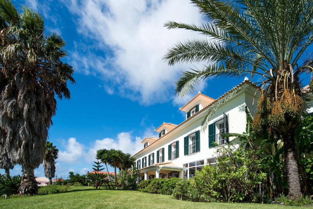 a white house with palm trees in the foreground at Quinta Alegre in Calheta