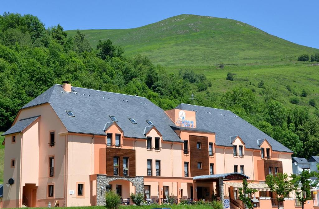 ein großes Gebäude mit einem Hügel im Hintergrund in der Unterkunft Hôtel Le Picors in Aucun