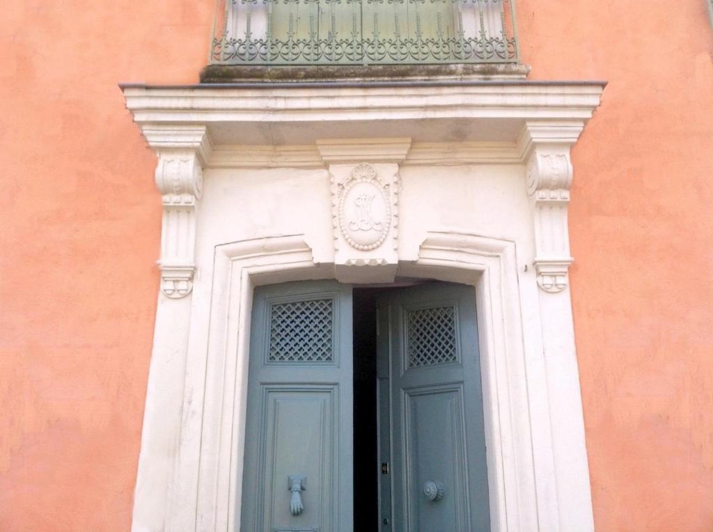 - un bâtiment avec une porte bleue et un balcon au-dessus dans l'établissement Aumes Sweet Home Chambre d'Hôtes, à Aumes