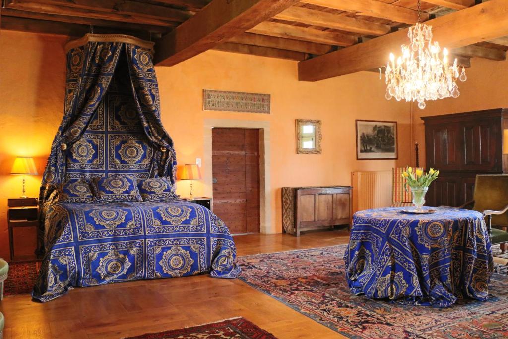 a bedroom with a bed with a table and a chandelier at Manoir de Malfarat in Charlieu