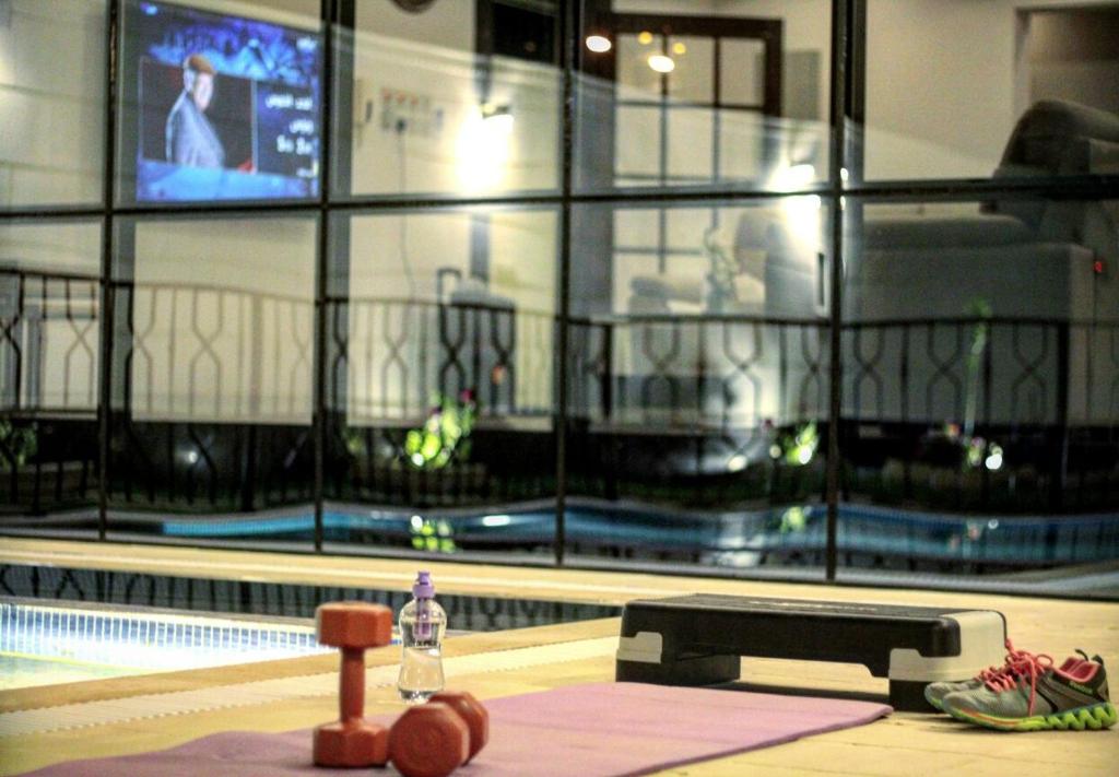 a gym with a swimming pool and a television at Chalet Le Porto in Unayzah