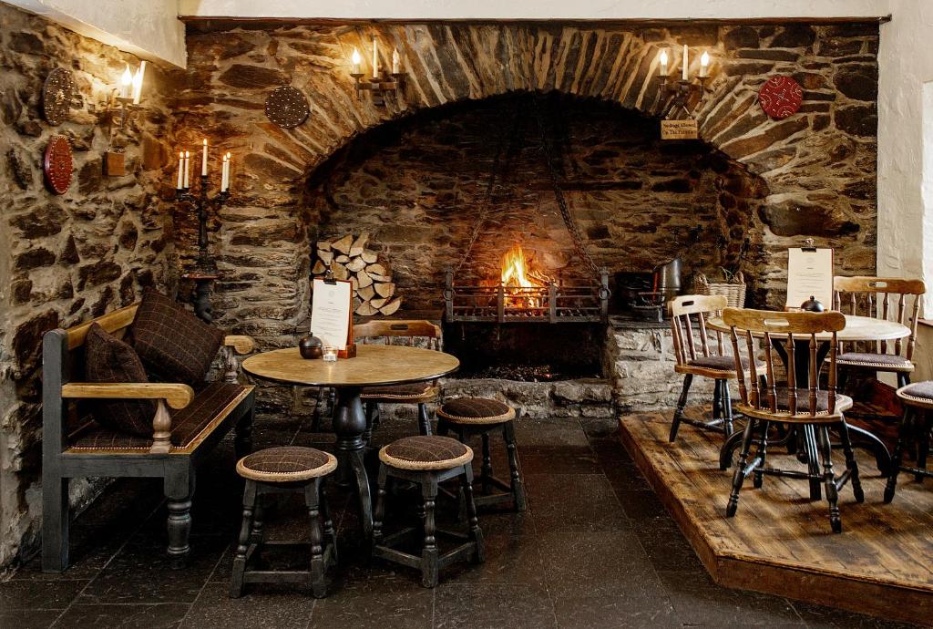 a room with tables and chairs and a stone fireplace at The Falls Of Dochart Inn in Killin