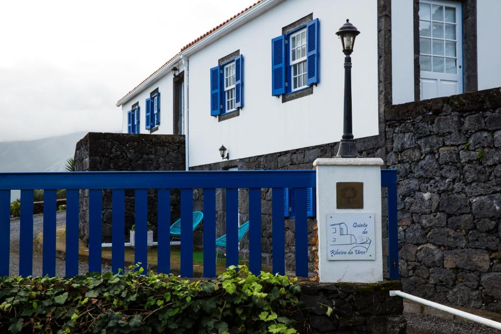 ein blau-weißes Haus mit einem blauen Zaun und einem Straßenlicht in der Unterkunft Quinta Da Ribeira Da Urze in Prainha de Cima