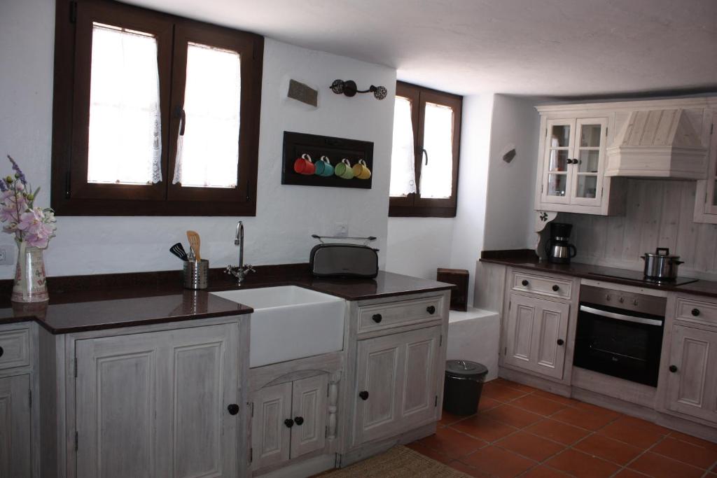 a kitchen with white cabinets and a sink at Casa Rural "La Molina" in Máguez