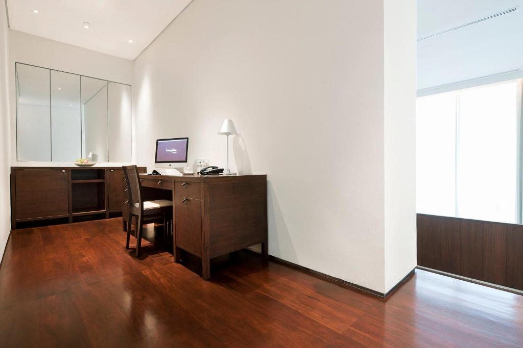 A built-in study with a computer, telephone and ample dark wood cabinetry beside a bright window.