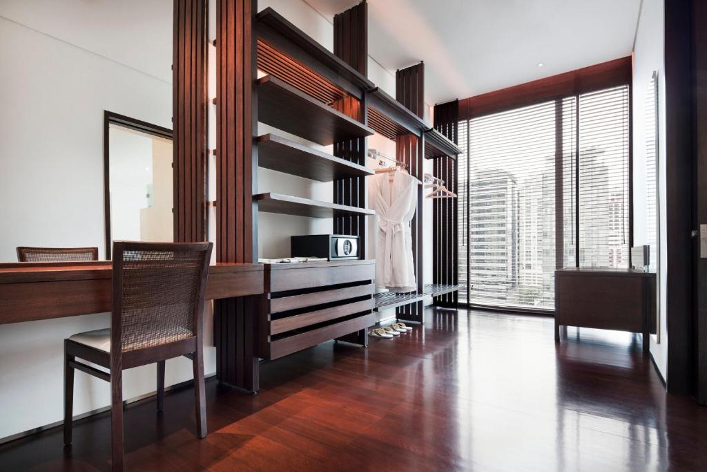A compact dressing and work area with a chair, desk surface, shelving and a bright city window.