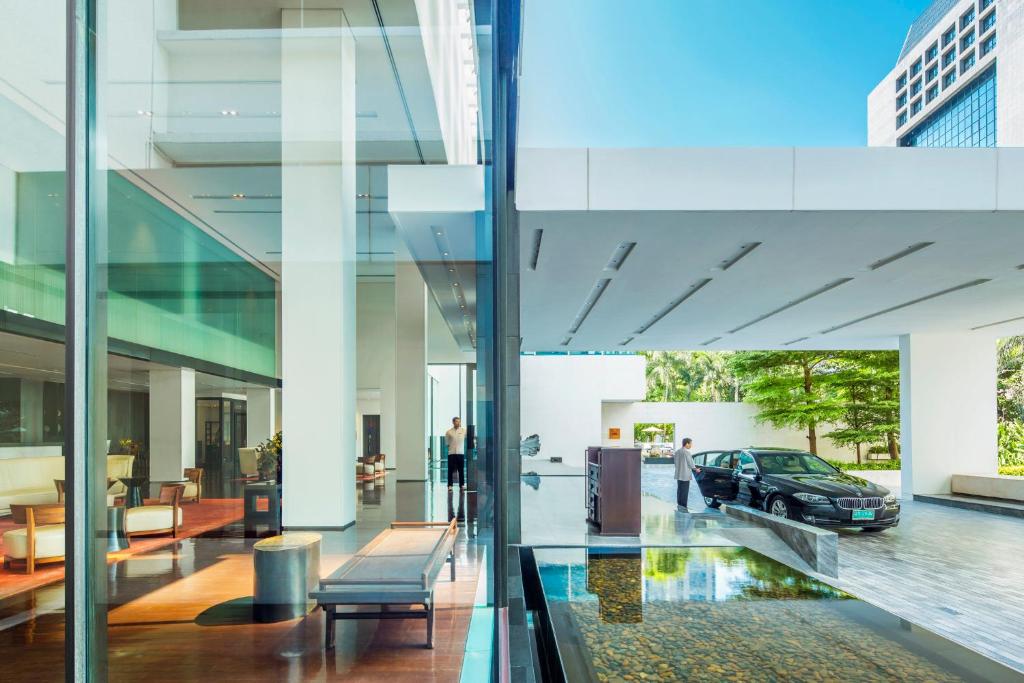 A bright glass-sided arrival lobby with a covered car drop-off.