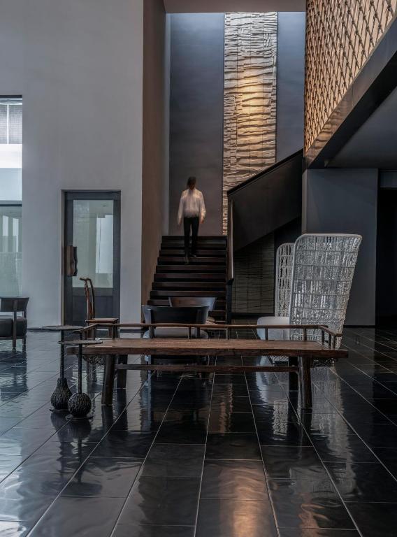 A dramatic lobby lounge faces a staircase and tall textured wall panel.