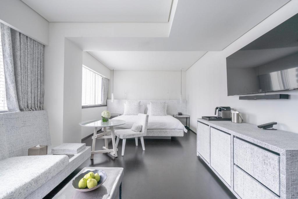 A bright open-plan room with a bed, sofa, dining table and compact kitchenette.