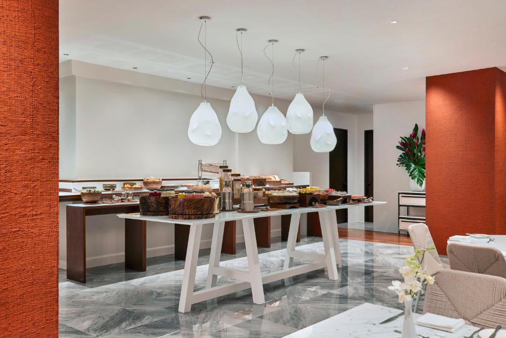 A bright buffet room displays food on long central tables.