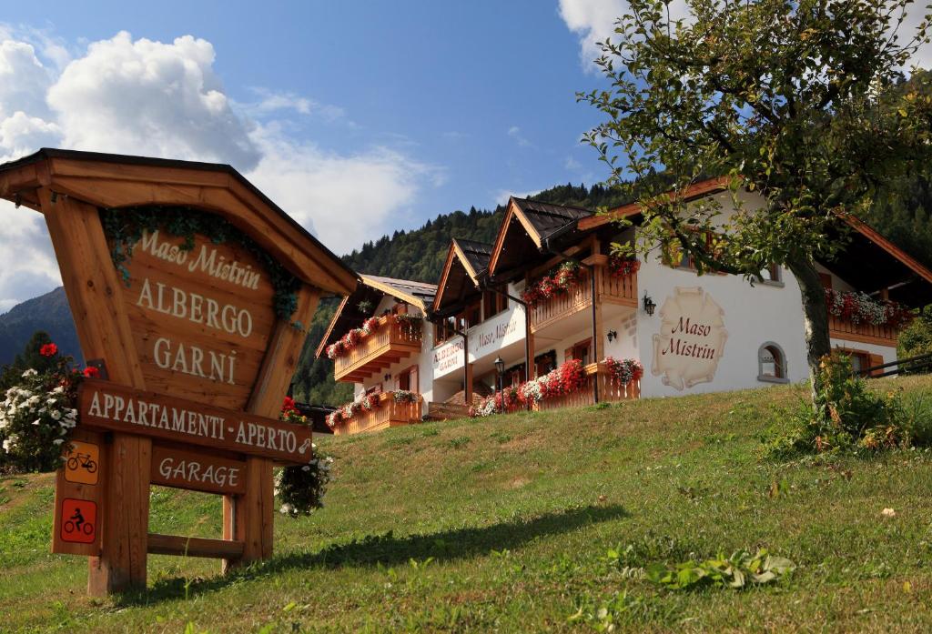 un cartello sull'erba di fronte a un edificio di Albergo Garnì Maso Mistrin a Madonna di Campiglio