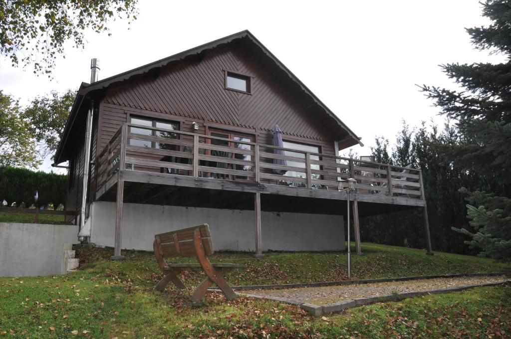 a house with a deck and a bench in front of it at Chalet Ardenne Mini in Rochehaut