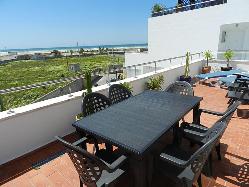einen schwarzen Tisch und Stühle auf einem Balkon mit Strandblick in der Unterkunft Casitasmanoli Conil in Conil de la Frontera