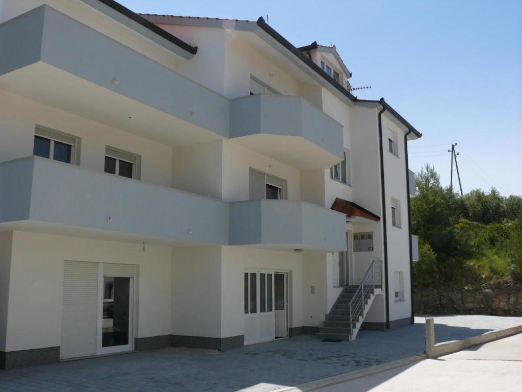 uma casa branca com uma escada em frente em Apartments and Rooms Stipe em Podstrana