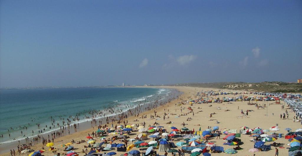 a crowd of people on a beach with umbrellas at Consolação Surf & Beach Apartment in Consolação