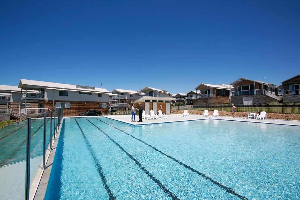 a swimming pool with people standing in front of some houses at Caves Coastal Bar & Bungalows in Caves Beach