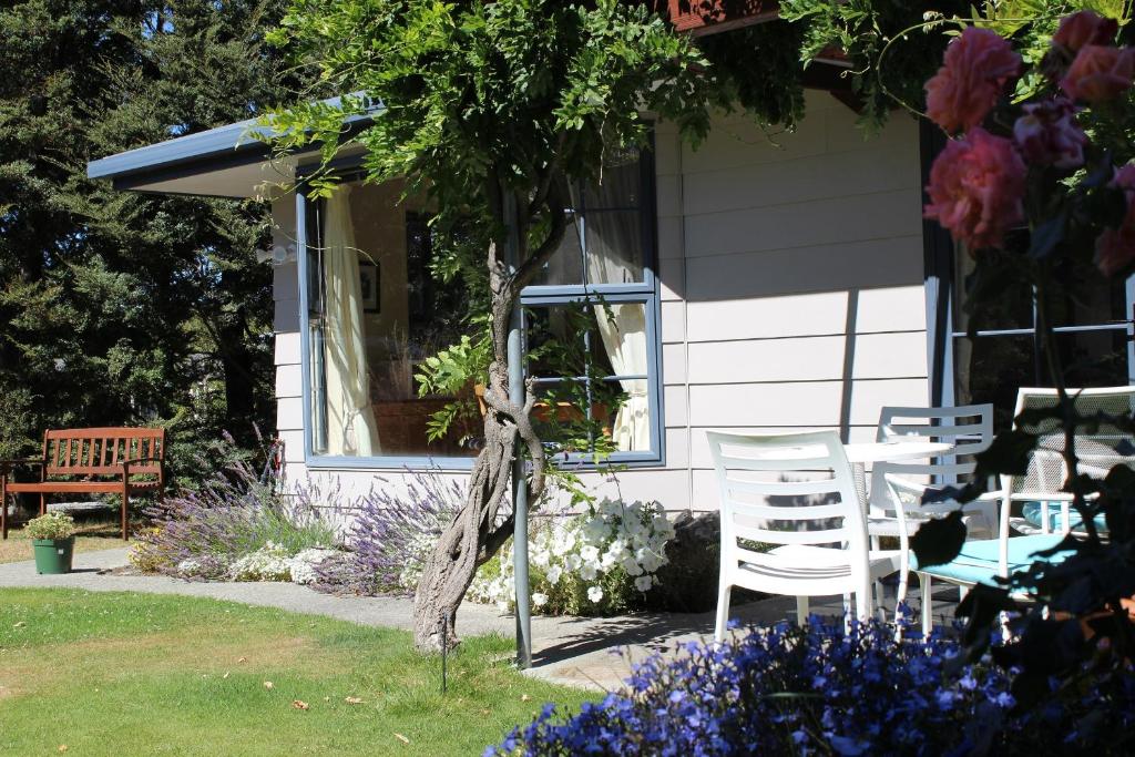 twee stoelen buiten een huis met bloemen bij Beech Cottage - Lake Tekapo in Lake Tekapo