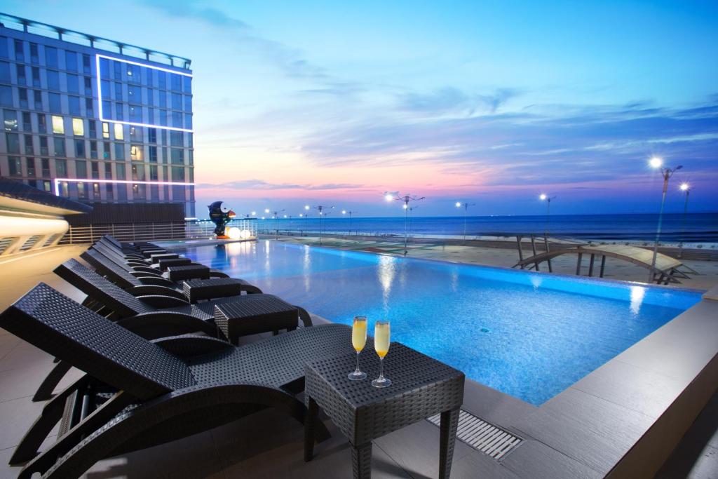 a pool on the roof of a building with chairs at Hotel Whistlelark by Best Western Signature Collection in Jeju