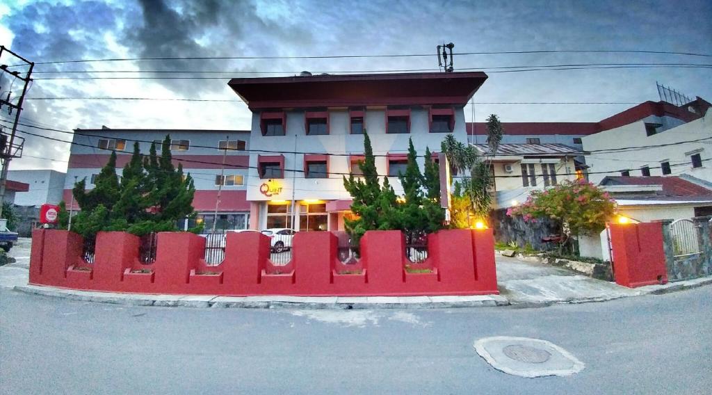 una valla roja frente a un edificio en Quint Hotel en Manado