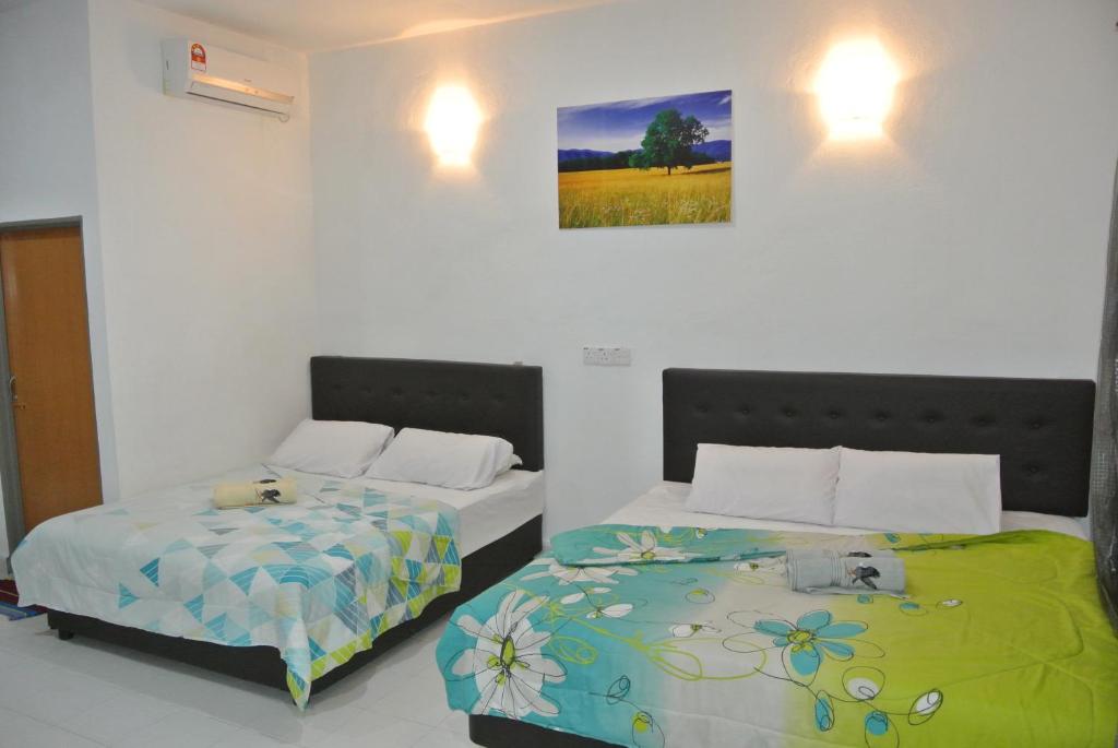 a bedroom with two beds and a picture on the wall at Wave Langkawi Inn in Pantai Cenang