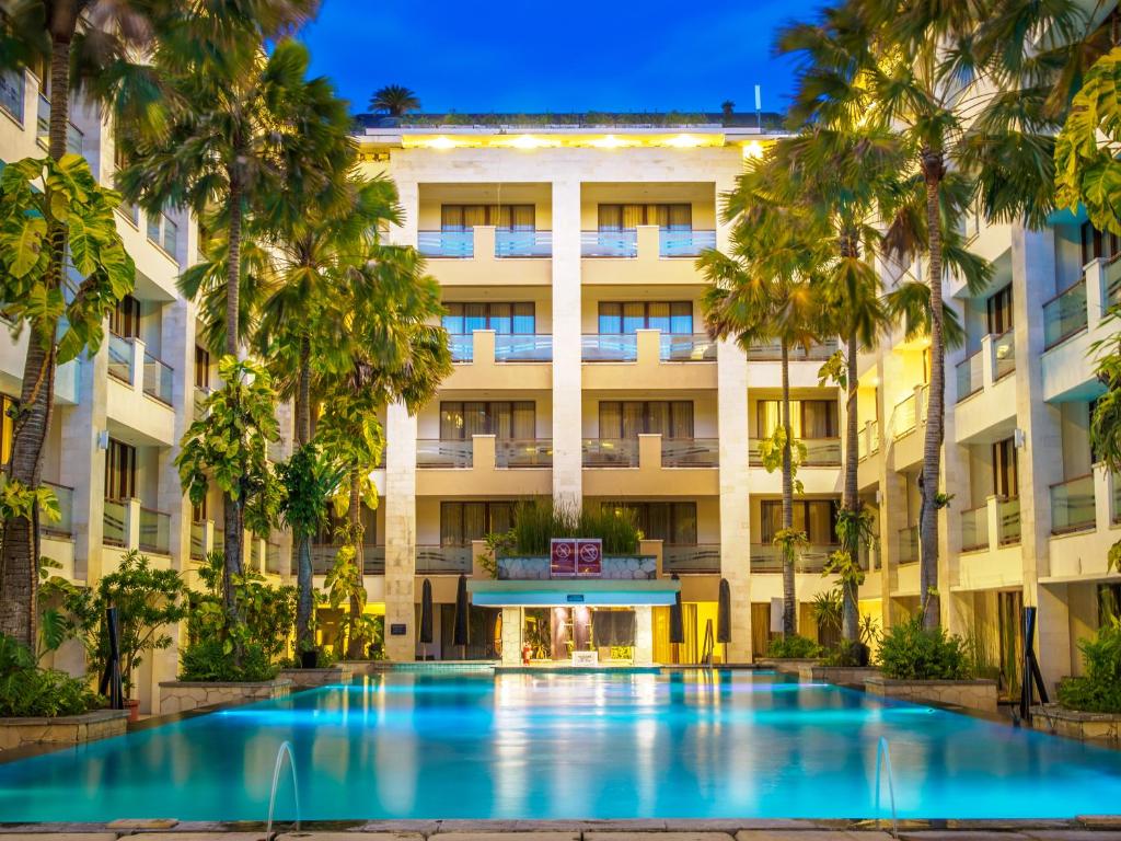a hotel with a large swimming pool in front of a building at Aston Kuta Hotel and Residence in Kuta