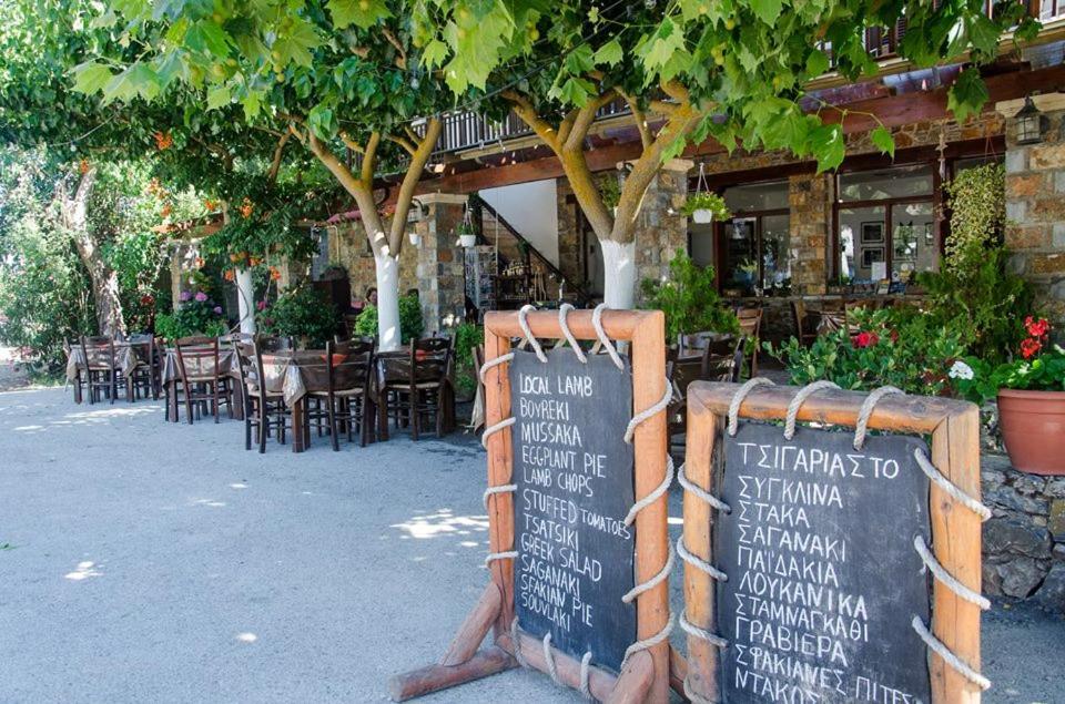 a sign in front of a restaurant with tables and chairs at Platanos Rooms in Anopoli Sfakion