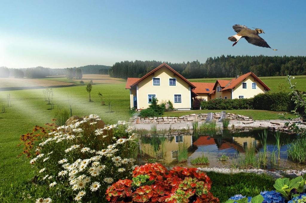 a bird flying over a pond in front of a house at Kibitzhof in Litschau