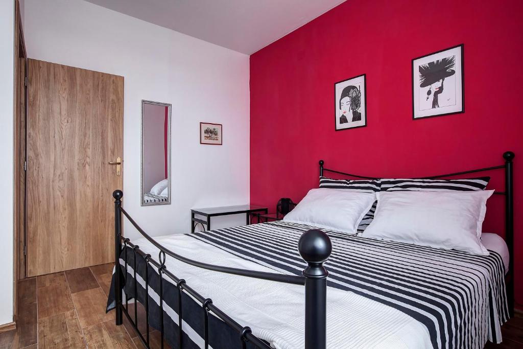 Un dormitorio con una cama en blanco y negro y una pared roja en Apartment Noa en Šibenik
