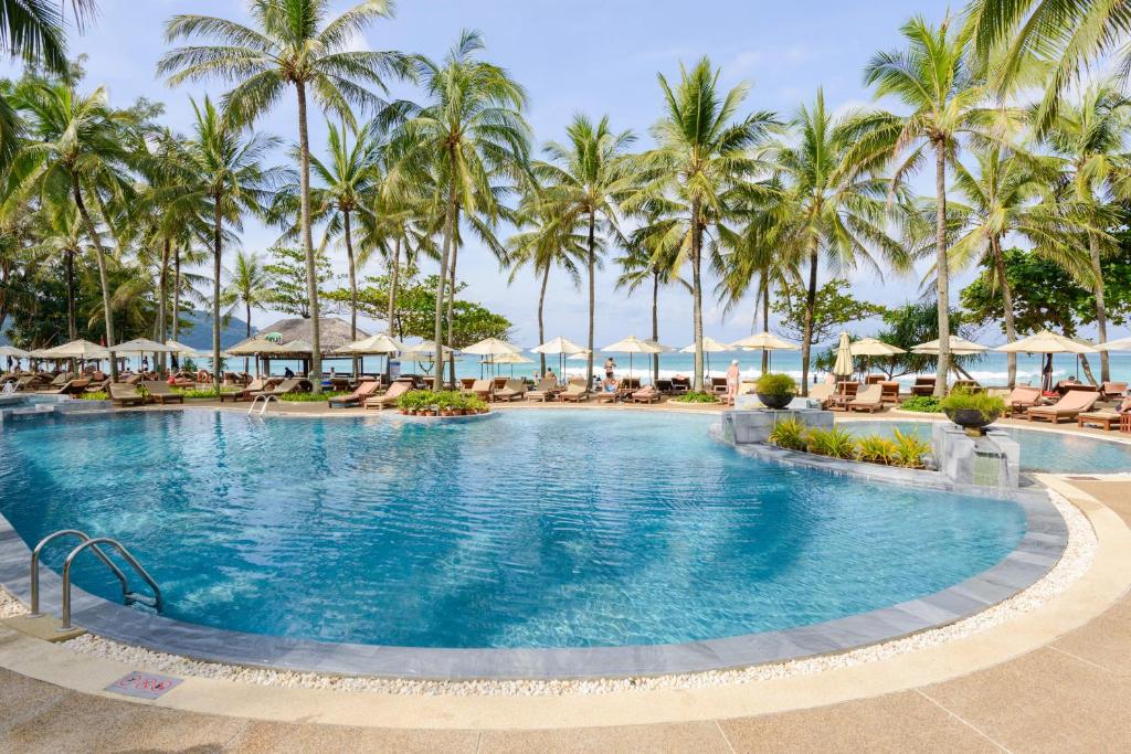 a large swimming pool with palm trees and umbrellas at Katathani Phuket Beach Resort - SHA Extra Plus in Kata Beach