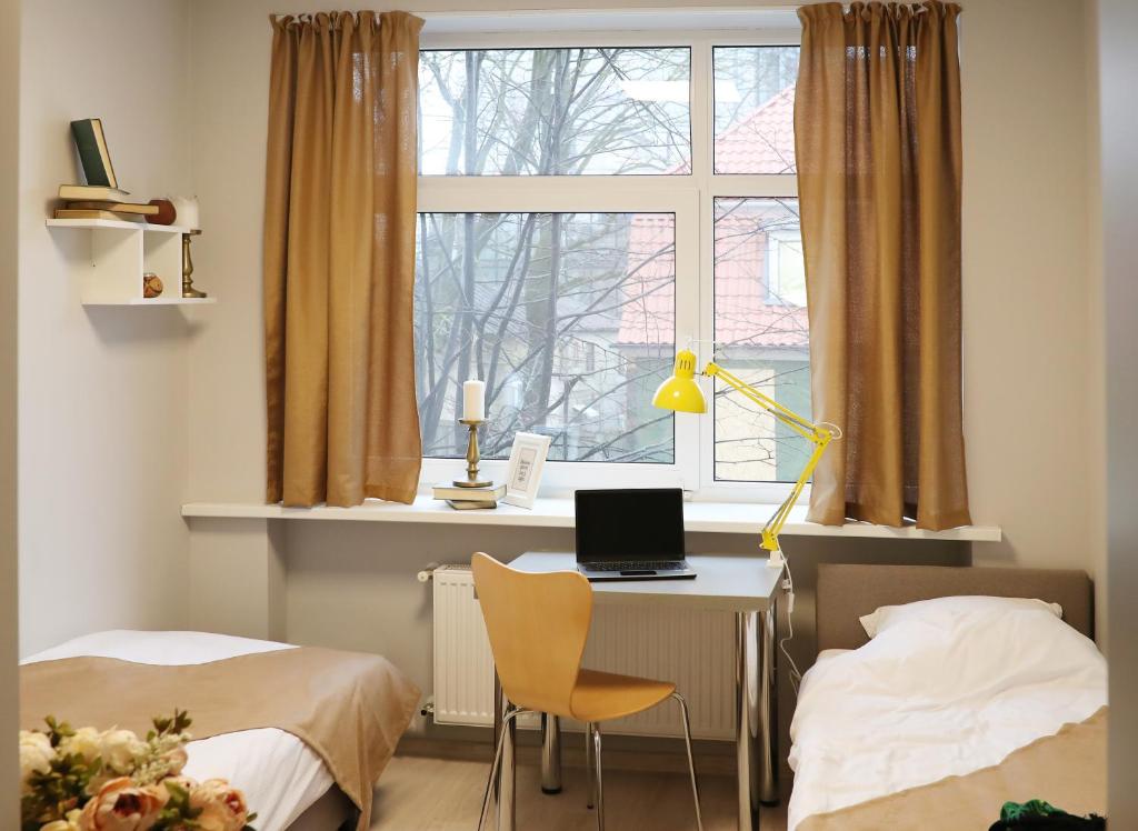 a bedroom with a desk and a window with a laptop at Bridge Hotel in Rīga