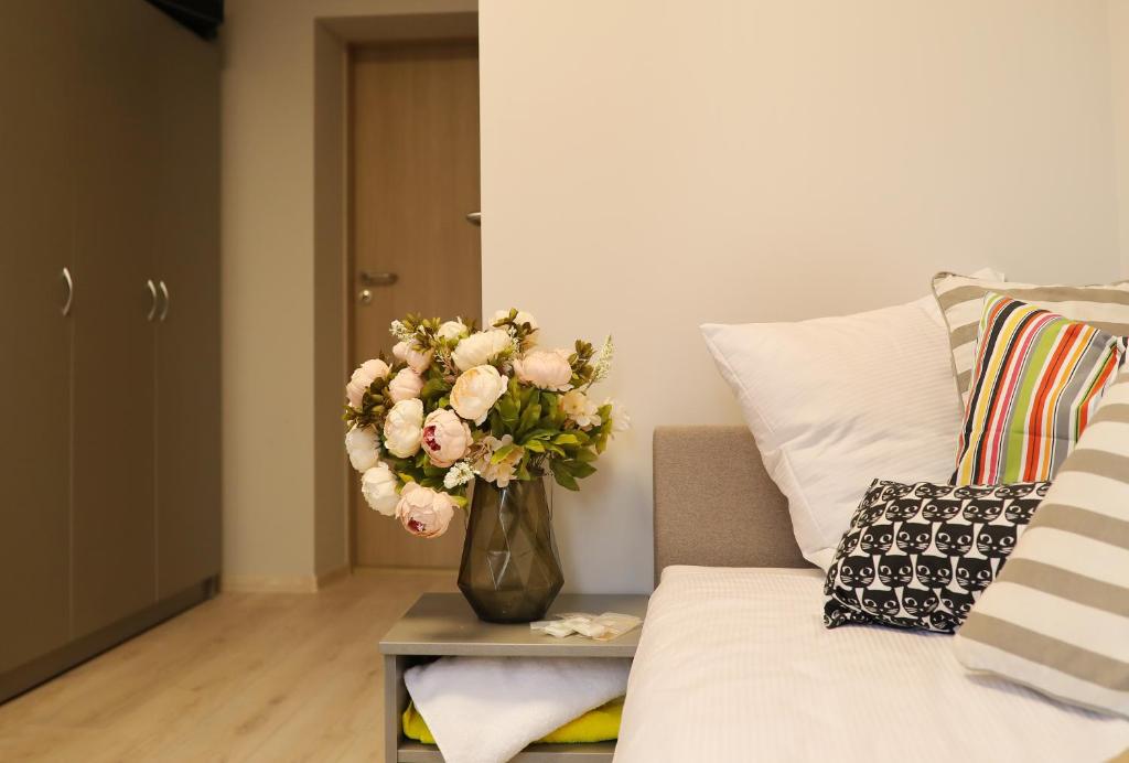 un jarrón de flores en una mesa junto a un sofá en Bridge Hotel, en Riga