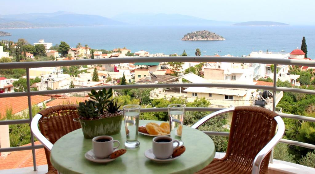 a table with two cups and plates of food on a balcony at Amaryllis Hotel Apartments in Tolo