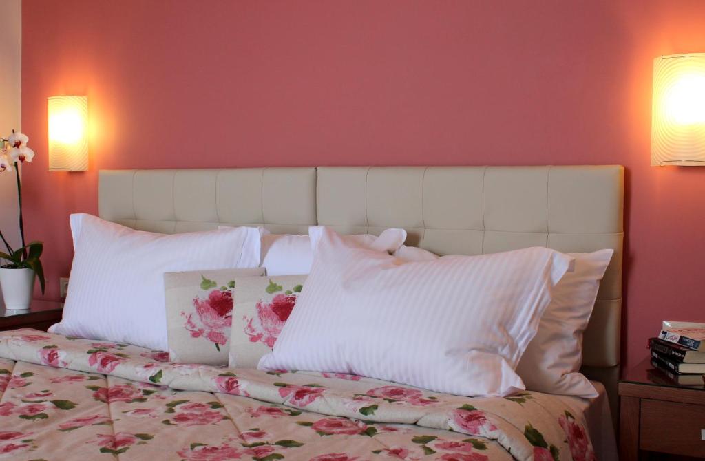 a bedroom with a white bed with pink walls at Amaryllis Hotel Apartments in Tolo
