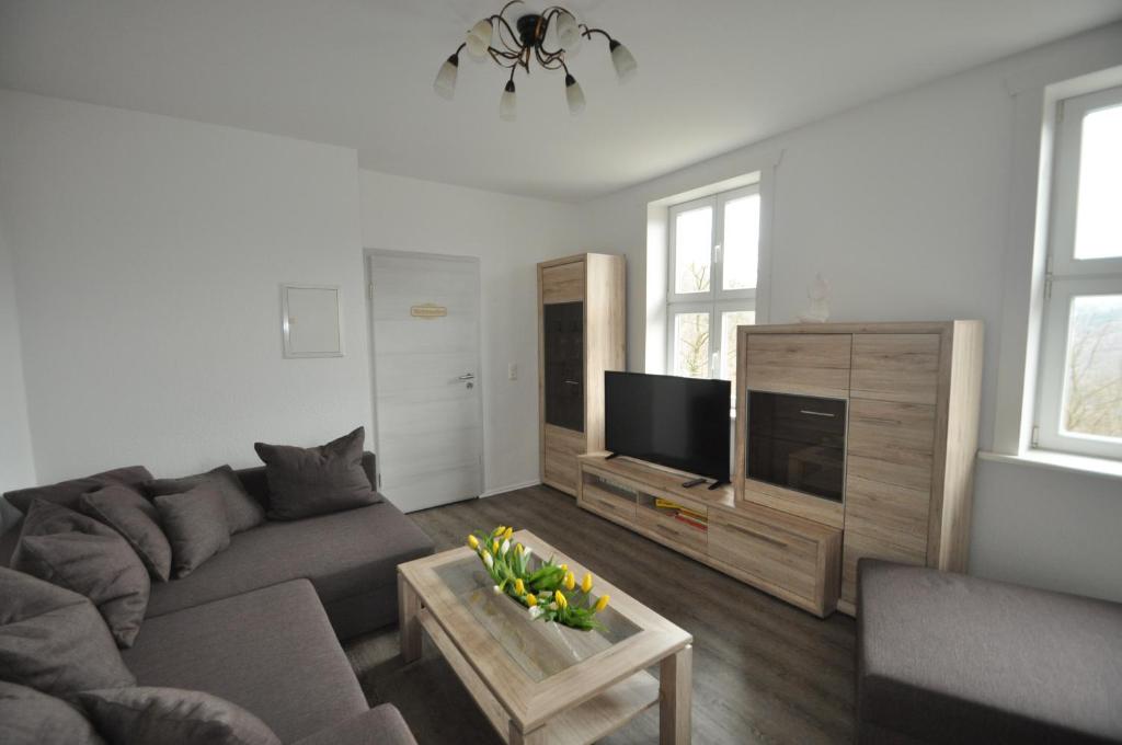 uma sala de estar com um sofá e uma televisão de ecrã plano em Gasthaus und Ferienwohnungen "Zum Büchsenmacher" em Wernigerode