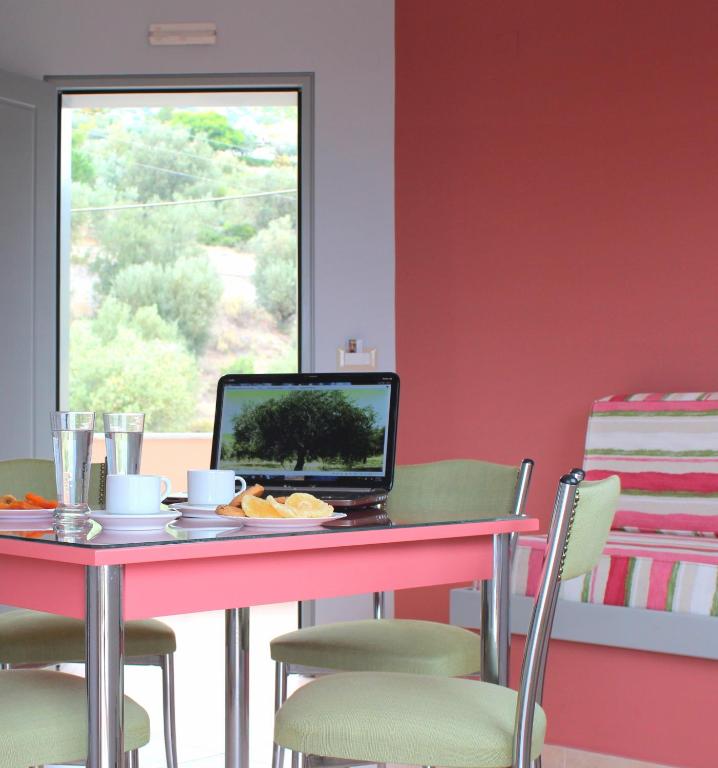 a dining room with a table with a laptop on it at Amaryllis Hotel Apartments in Tolo