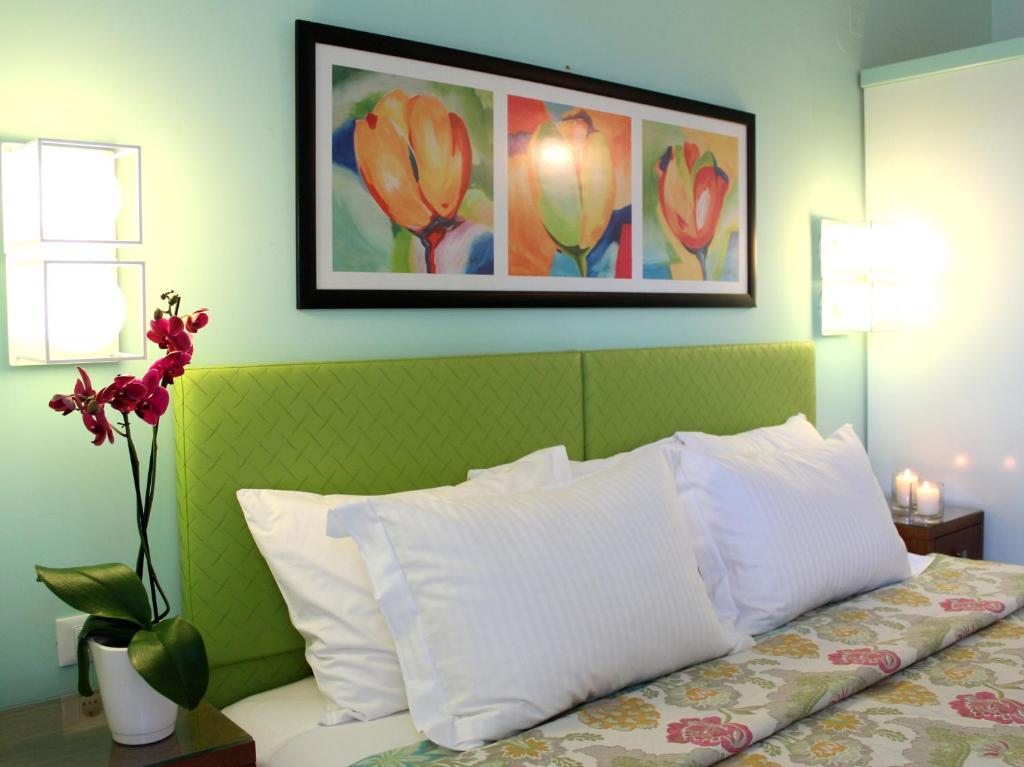a bedroom with a bed with white pillows and a painting at Amaryllis Hotel Apartments in Tolo