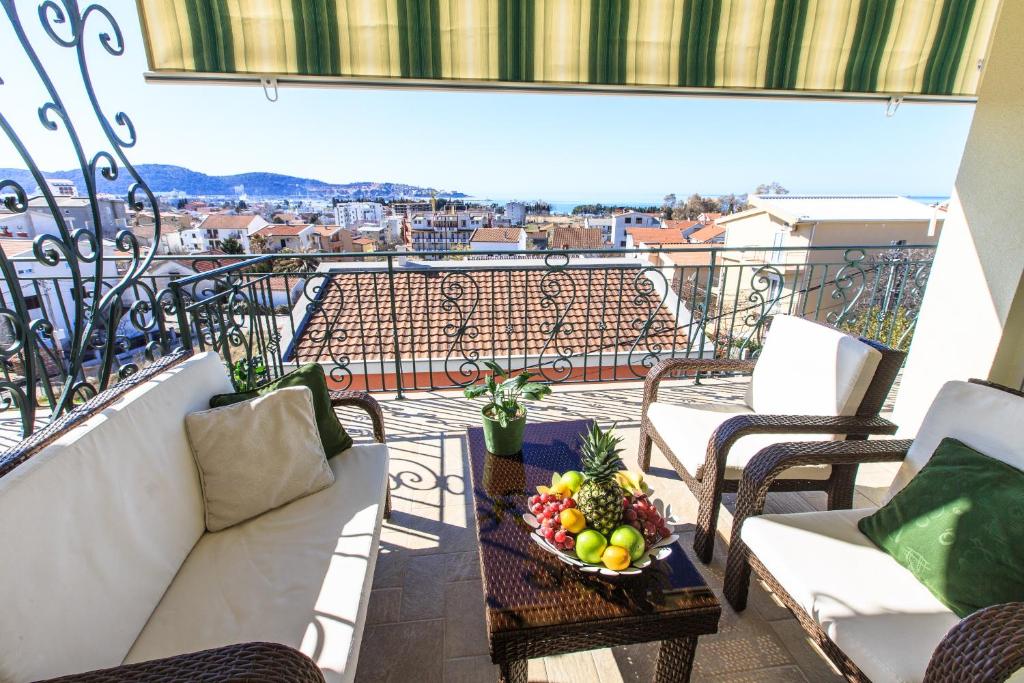 a balcony with a couch and a bowl of fruit on a table at Apartments Aleksić in Bar