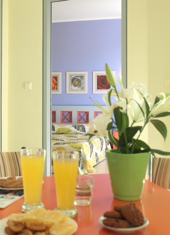 a table with a vase of flowers and two glasses of orange juice at Amaryllis Hotel Apartments in Tolo