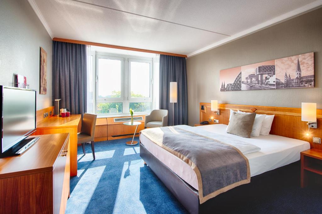 a hotel room with a bed and a television at Leonardo Hotel Köln Bonn Airport in Cologne