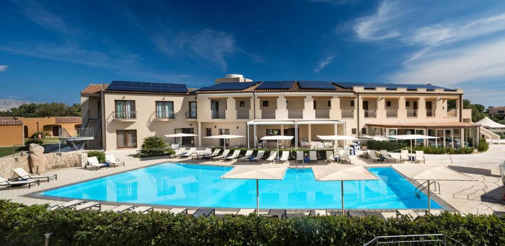 un grand bâtiment avec une piscine et des parasols dans l'établissement Terradimare Resort&Spa, à San Teodoro