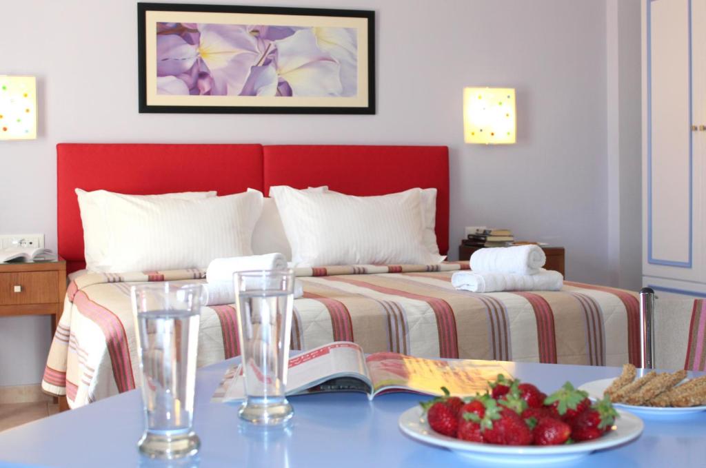 a bedroom with a bed with a book and a table with fruit at Amaryllis Hotel Apartments in Tolo