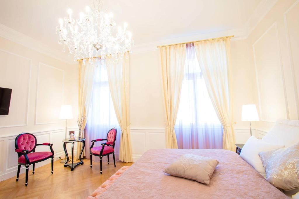 ウィーンにあるImperium Residence - Experience the most Luxurious Apartment in Vienna Centerのベッドルーム1室(ベッド1台、椅子2脚、シャンデリア付)