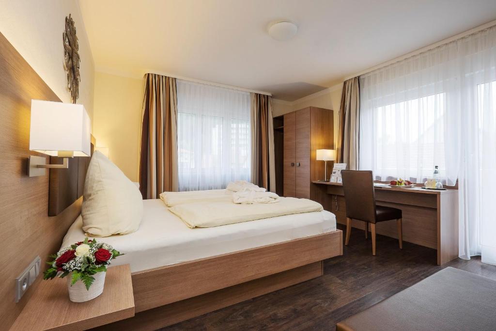 ショップハイムにあるHotel-Gasthaus Adlerのベッドとデスクが備わるホテルルームです。