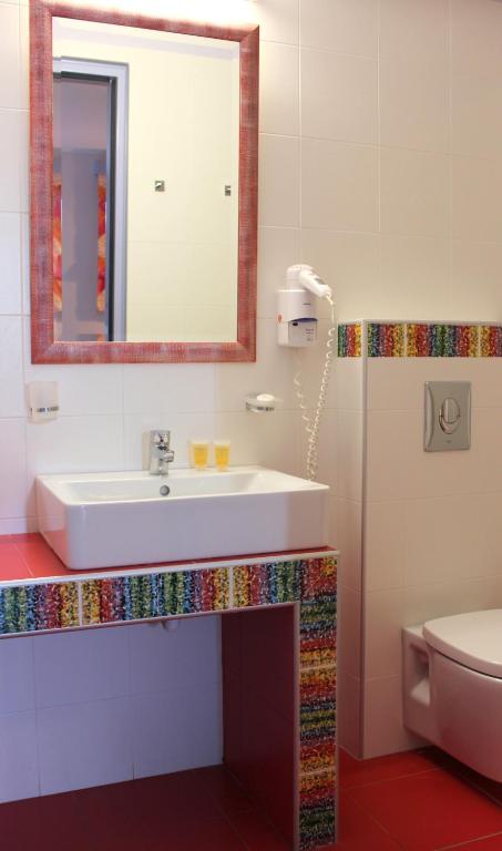a bathroom with a sink and a mirror and a toilet at Amaryllis Hotel Apartments in Tolo