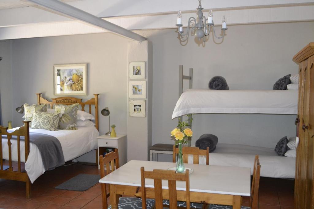 a bedroom with two beds and a table and chairs at Rooiheuwel Cottage in Wellington