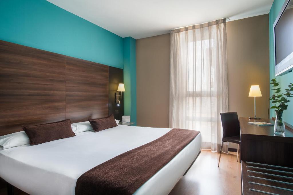 a hotel room with a large bed and a desk at Eurostars Rey Fernando in Zaragoza