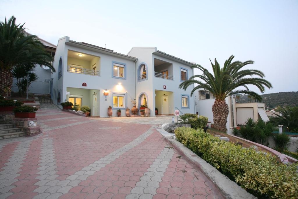 ein großes weißes Haus mit Palmen und einer Auffahrt in der Unterkunft Aigli Apartments in Nea Anchialos