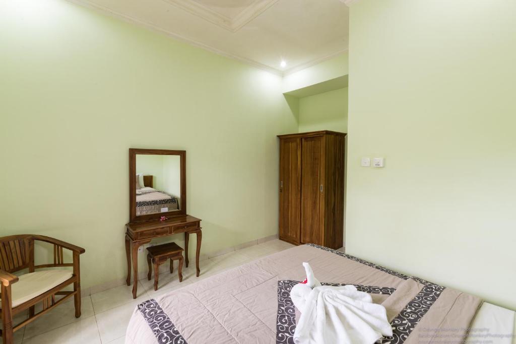 a bedroom with a bed and a chair and a mirror at Sudiana House in Ubud
