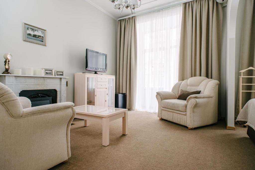 a living room with two chairs a table and a tv at Anabel at Nevsky 88 in Saint Petersburg